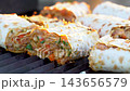 Sizzling lavash is grilled to perfection, stuffed with flavorful minced meat and vibrant vegetables. Watch as each roll captures mouthwatering goodness on the grill. 143656579