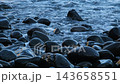 Ocean waves wash over smooth dark volcanic stones on a rugged beach, Madeira, Portugal 143658551