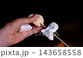 Threading Halloween ghost and pumpkin shaped marshmallows onto a wooden skewer while preparing festive sweet treats for roasting over a campfire 143658558