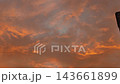 Orange illuminated clouds slowly shift across a moody evening sky, with a dark building edge visible along the right side of the frame 143661899