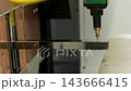 Automated CNC laser cutting machine processing a square metal pipe with bright 143666415