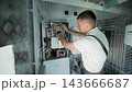 HVAC Technician Adjusting Heat Pump and Boiler System in Modern Mechanical Room 143666687