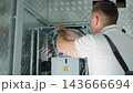 HVAC Technician Adjusting Heat Pump and Boiler System in Modern Mechanical Room 143666694