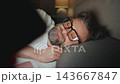 A man in eyeglasses lying in bed using smartphone late at night 143667847
