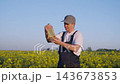 Worker farmer gives a gesture of approval for quality of rapeseed oil. Portrait, Farmer Inspecting Bottle Of Rapeseed Oil, Showing Agricultural Production, Quality Check, Sustainable Energy Crop. 143673853