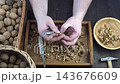 Male hands clean nuts with a nut cracker. Close-up. Walnut in shell top view. 143676609
