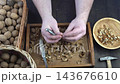 Male hands clean nuts with a nut cracker. Close-up. Walnut in shell top view. 143676610