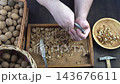 Male hands clean nuts with a nut cracker. Close-up. Walnut in shell top view. 143676611