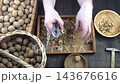 Male hands clean nuts with a nut cracker. Close-up. Walnut in shell top view. 143676616