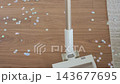 Vacuum cleaner picking up colorful star shaped confetti scattered on wooden floor. Concept of after party cleanup, removing decorations and cleaning up celebration mess at home 143677695