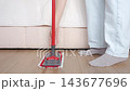 Person attaches microfiber cleaning pad to flat mop on wooden floor at home. Concept of household chores and housekeeping 143677696
