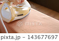 Closeup of hand moving electric steam iron over fabric to smooth wrinkles. Concept of ironing clothes and everyday household chores 143677697