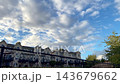 Timelapse, Modern townhouses stand behind a black chain-link fence under a blue sky filled with white clouds 143679662