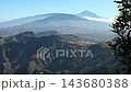 A green branch edges a wide Anaga panorama with Mount Teide rising pale through afternoon haze. Layered island scenery built for travel and background use. 143680388