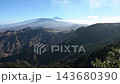 Sunlit ridge lines stretch across the Anaga interior toward a pale silhouette of Mount Teide. Tenerife's volcanic backbone captured in one sweeping mountain panorama. 143680390