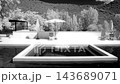 An infrared timelapse shows a modern luxury swimming pool and patio with lounge chairs and umbrellas against a wooded hill 143689071