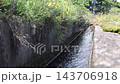 Water flowing through an agricultural irrigation channel. A concrete channel surrounded by grass. 143706918