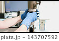 Gloved hands adjusting metal testing press compression head over stainless steel platform in laboratory setup for precision measurement and quality inspection of materials under load testing 143707592
