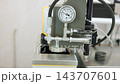 Close-up industrial pressure gauge and stainless steel piping showing controlled pressure on laboratory bench with connected hoses and fittings for measurement testing and calibration purposes. 143707601