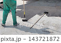 A construction worker applies a bituminous waterproofing layer to an exposed floor surface using a paint roller. This protective coating prevents rainwater leakage into the structure below. 143721872