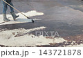 A construction worker applies a bituminous waterproofing layer to an exposed floor surface using a paint roller. This protective coating prevents rainwater leakage into the structure below. 143721878