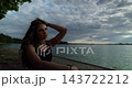 A contemplative woman finds herself by the beautiful lake, enjoying the peaceful dusk hours 143722212