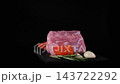 A fresh pork cut slowly turns on a black slate board with rosemary, garlic, tomatoes and pepper arranged nearby. Raw meat food concept 143722292