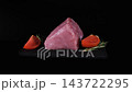 A raw pork cut rotates on black slate beside rosemary, garlic, tomatoes and black pepper against a black background. Fresh meat concept 143722295