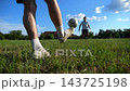 Professional footballers passing soccer ball on green grass field. Sportsmen kicking ball during an intensive dynamic training session. Young men practicing soccer passes on stadium at sunny day 143725198