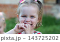 Portrait of cute little girl smiling outdoor on green garden. Beautiful cheerful small child looking into camera with a joyful expression. Happy innocent kid enjoying childhood moments in summer 143725202
