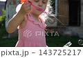 Beautiful blonde child blowing soap bubbles outdoor on bright sunny day. Cute little girl playing with bubbles in green summer garden. Innocent kid enjoying happy childhood moments at nature. Slow mo 143725217