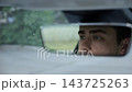 Male blue eyes of driver reflecting in rearview mirror while riding modern electric car. Young man look concentrated to urban road while operating motor vehicle capturing focused gaze during city trip 143725263