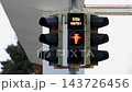 German pedestrian traffic light displays Bitte warten - Please wait in English. Red standing figure changes green walking Ampelmann, indicating safe crossing for pedestrians at urban intersection 143726456
