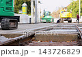 Municipal workers repair tram tracks in Magdeburg, Germany, using excavator and construction machinery. Close view of railway rails and concrete sleepers shows urban infrastructure maintenance 143726829