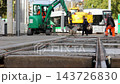 Municipal workers repair tram tracks in Magdeburg, Germany, using excavator and construction machinery. Close view of railway rails and concrete sleepers shows urban infrastructure maintenance 143726830