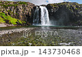 Powerful waterfall cascading over fractured basalt cliff into emerald pool from low waterline viewpoint, Iceland 143730468