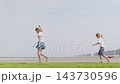 Girl and boy walking barefoot with kites on green algae shore side view tilt camera movement 143730596