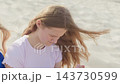A teenage girl is sitting on the beach and looking down slow motion wind blows hair close-up 143730599
