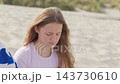 A sad daughter sits next to her mother who is talking on the phone sandy dunes by the sea, 35 years old woman and 15 years old girl close-up camera movement 143730610