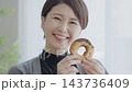 一位女士正在吃甜甜圈。 143736409