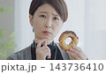 一位正在節食的女士正在猶豫要不要吃一個甜甜圈。 143736410