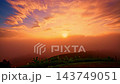 A cinematic drone aerial view of sunrise casting warm golden light over a misty mountain valley. Layers of fog drift between forested hills while distant peaks glow beneath a colorful dawn sky, creati 143749051