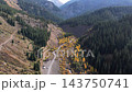 An aerial view showing Lake Kaindy beyond the forest ridge, flying along the stream beds and mountain paths in autumn. 143750741