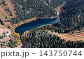 An aerial view showing Lake Kaindy receding from a coniferous ridge and moving into the depths of the valley. 143750744