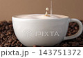 Drop of milk falling in a white cup with black coffee. Side View. Slow Motion. Coffee droplet. Roasted coffee beans background. Freshly brewed latte cappuccino. Close up. Coffee product advertising 143751372