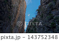 Timelapse of white cumulus clouds moving fast through a narrow gap between steep rocky canyon cliffs in Presa de Isber gorge, Spain. 143752348