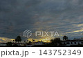 Sunrise timelapse over a coastal Spanish town with dense textured clouds and palm tree silhouettes as sunlight breaks through at dawn. 143752349