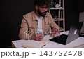 Young professional writing in a notebook while using a laptop 143752478