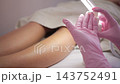 Esthetician applying moisturizing lotion on woman's legs 143752491