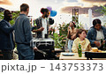 Friends gesturing toward man cooking on rooftop grill with tongs, group smiling and having fun together at BBQ party outdoors. Barbecue and relaxed social gathering. 143753373